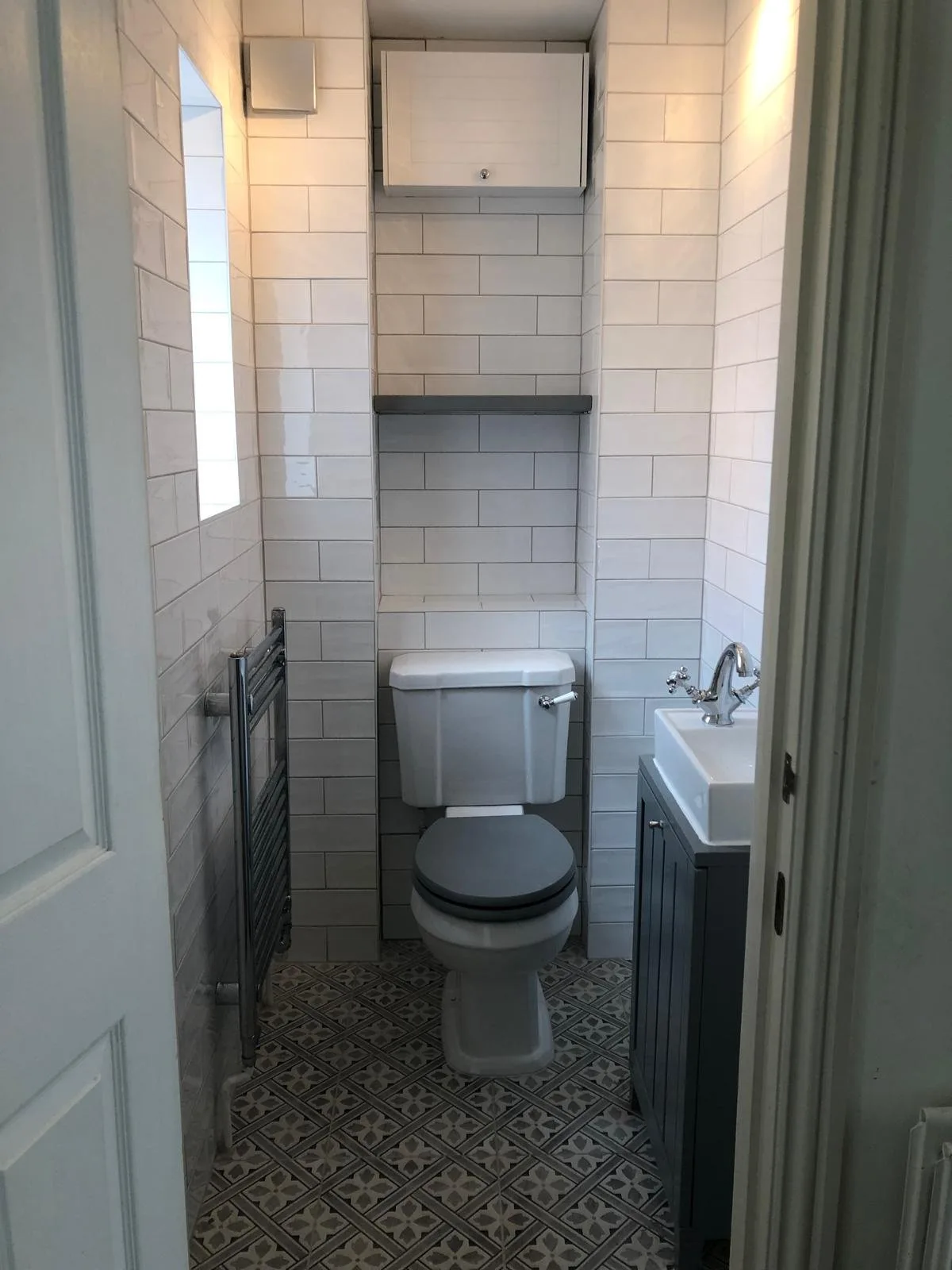Downstairs cloakroom in white metro tiles with a navy panelled vanity basin