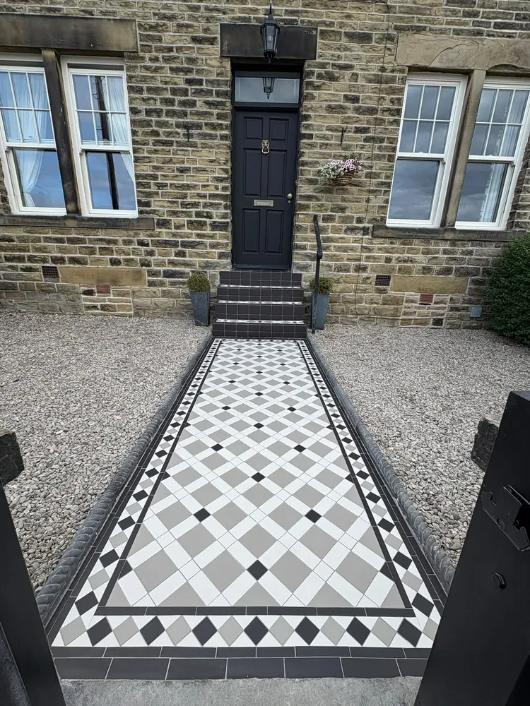 Diamond-patterned front path in white, grey and black with a black-and-white triangle border, leading to steps faced in plain charcoal tiles